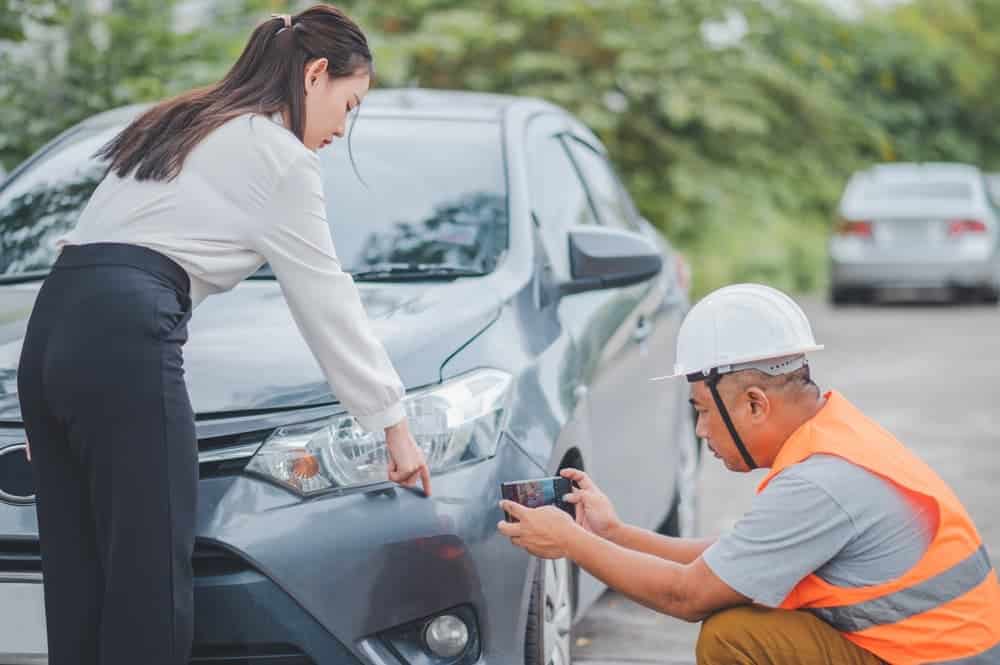 Insurance agent inspects customer's crashed car, concept for accident, claim assistance.