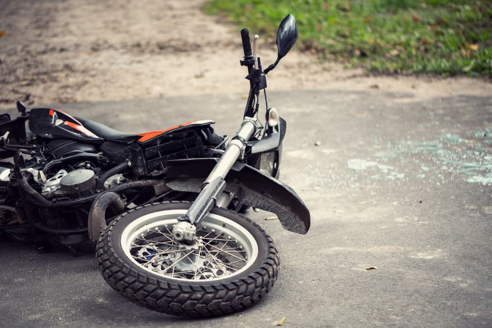 Motorcycle damaged on the roadside following a traffic incident.