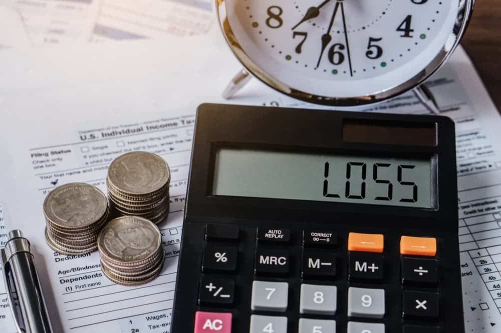 The word "LOSS" displayed on a calculator, symbolizing the loss, bankruptcy, and crisis. It reflects financial crisis, economic downturn, recession, inflation, with a graph chart depicting a decline.