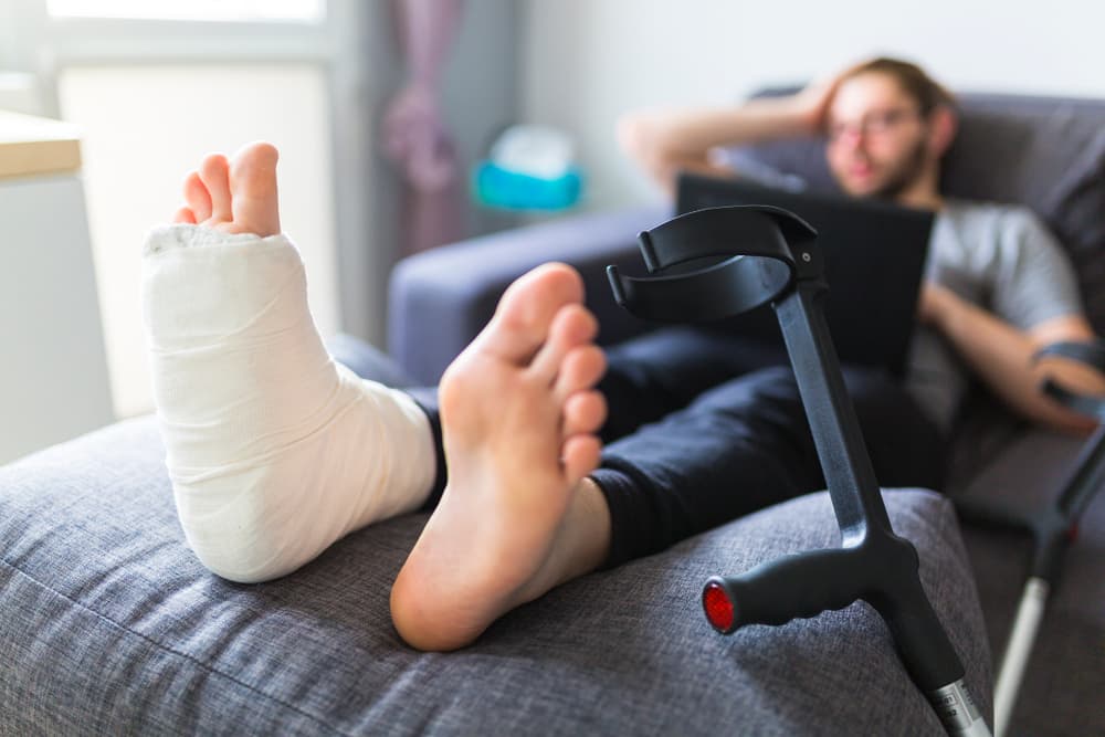 A boy with crutches and a broken leg at home after an accident.