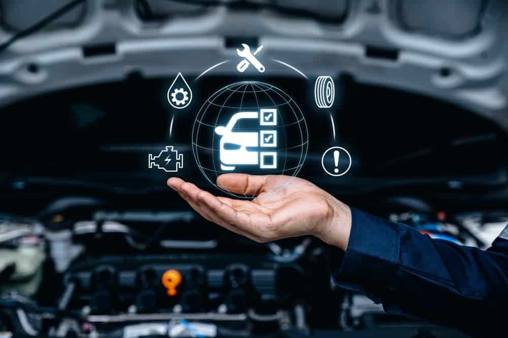 A mechanic's hand presenting digital icons of car maintenance and diagnostics above an engine.