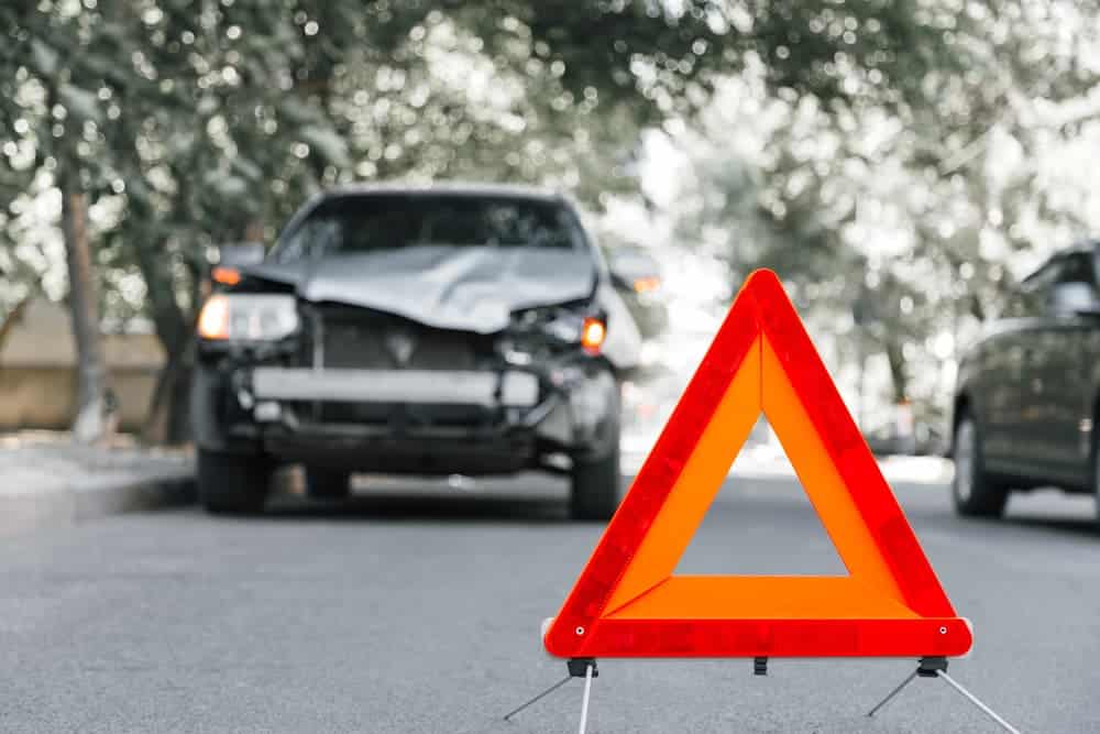 Red emergency stop triangle sign on road in car accident scene. Broken SUV car on road at traffic accident. Car crash traffic accident on city road after Hit and Run.