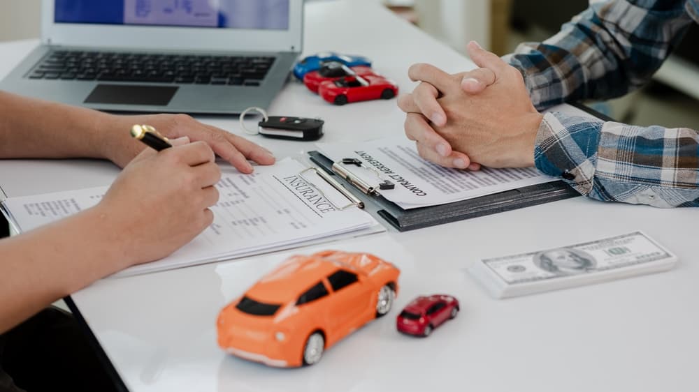 The car dealer calculates interest rates and car insurance policies while providing financial and insurance services, giving the customer time to review the terms and conditions.