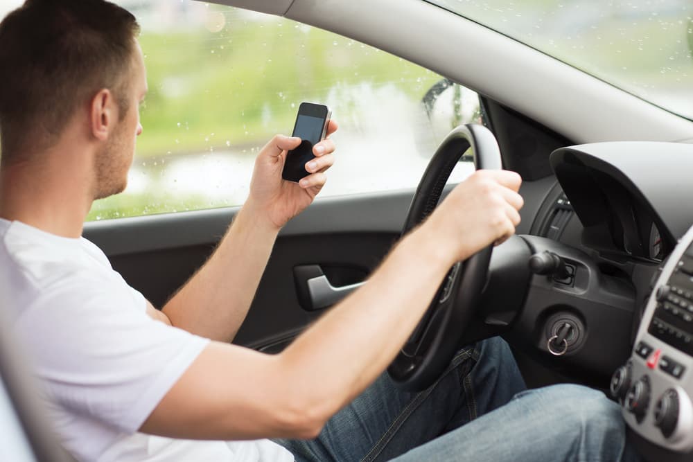 Transportation and vehicle concept &ndash; a man using his phone while driving.