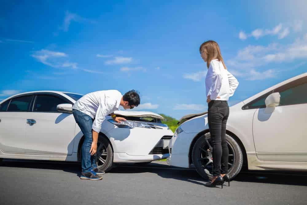 Two drivers engaged in a heated argument after a car accident on the road.