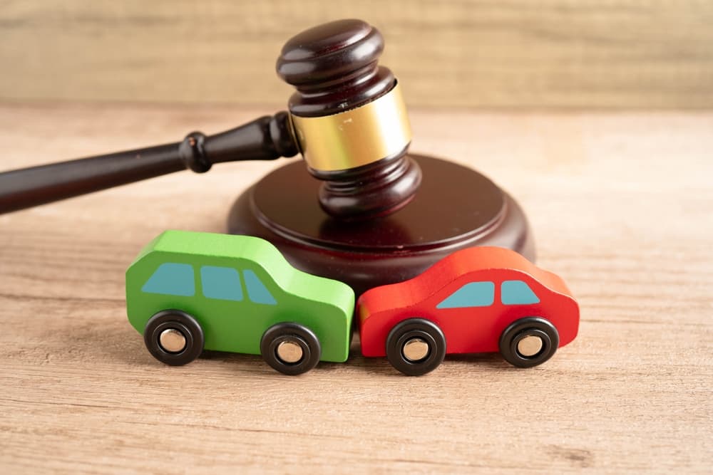 Car accident lawsuit and insurance, judge&rsquo;s gavel with a car model.